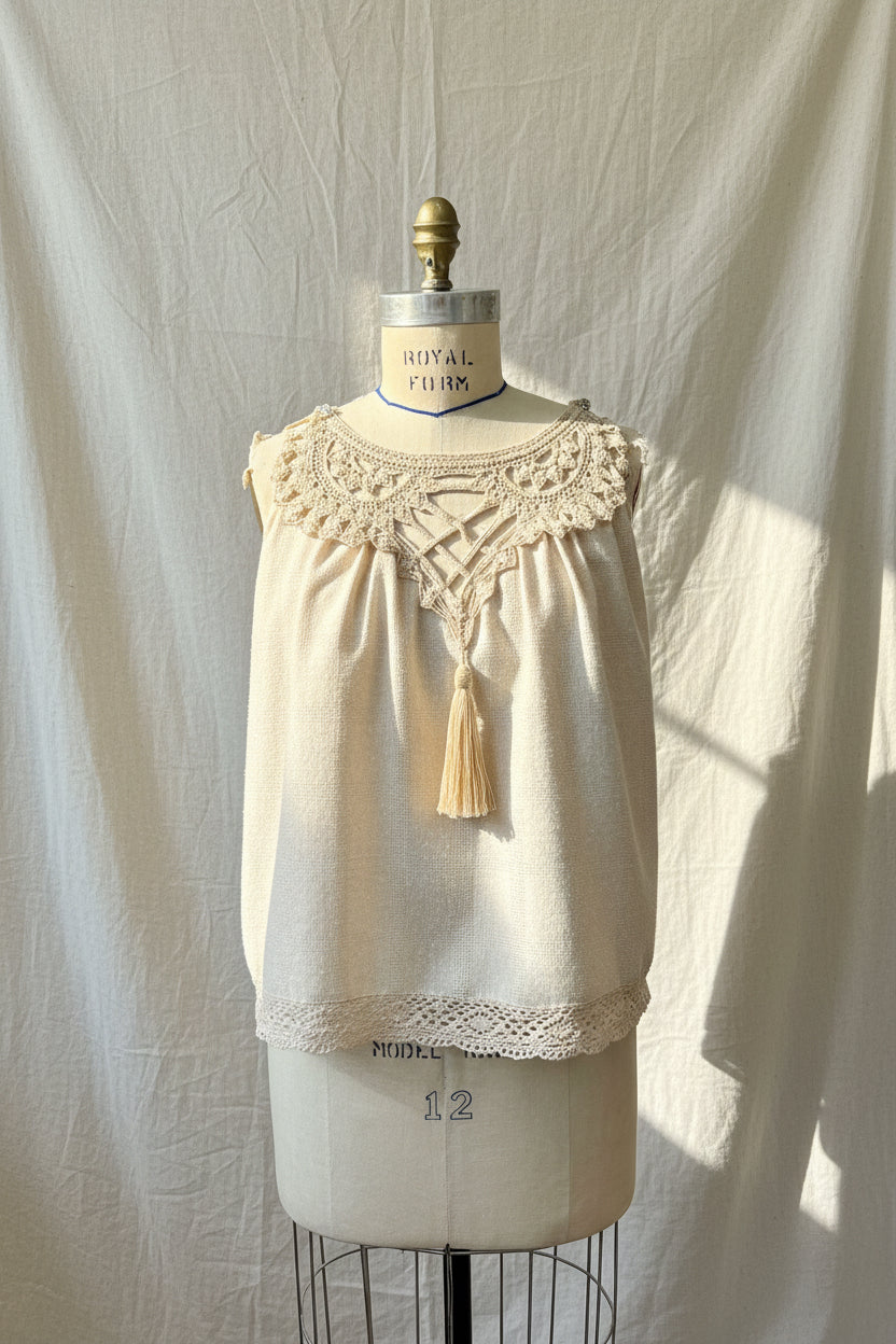 Beige lace top on a mannequin against a white curtain