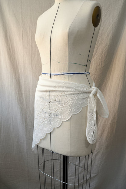 White lace triangular scarf with ties on a mannequin against a neutral background