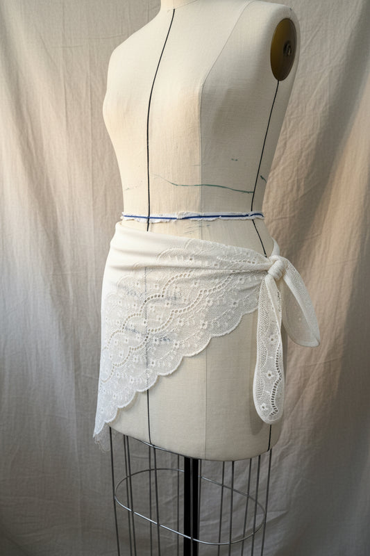 White lace triangular scarf with ties on a mannequin against a neutral background