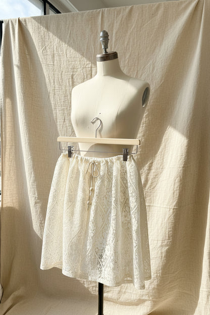 Lace shorts hanging on a wooden hanger against a sheer curtain backdrop