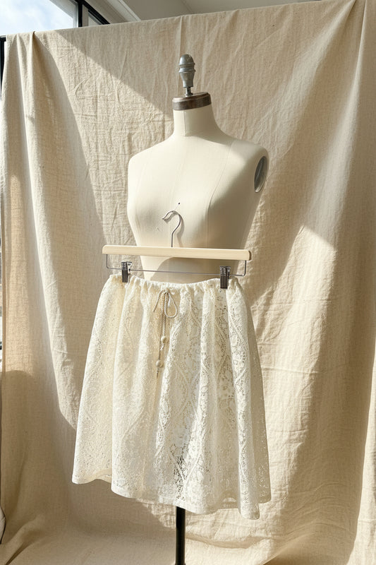 Lace shorts hanging on a wooden hanger against a sheer curtain backdrop
