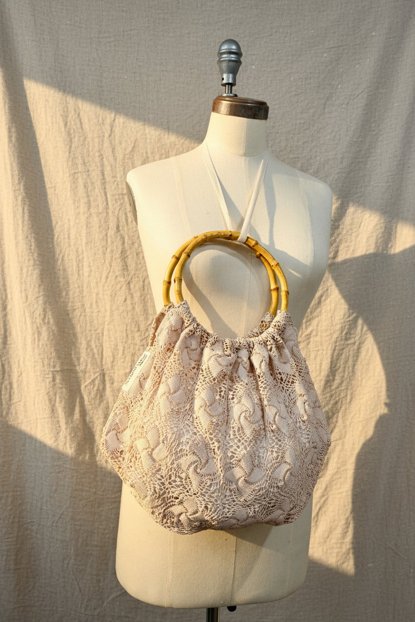 Decorative handbag with floral lace details on a mannequin against a neutral background