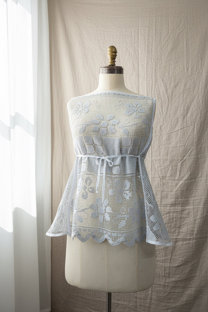 Blue-grey lace dress on a mannequin against a beige curtain background