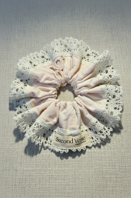 Pink scrunchie with lace on a textured beige background