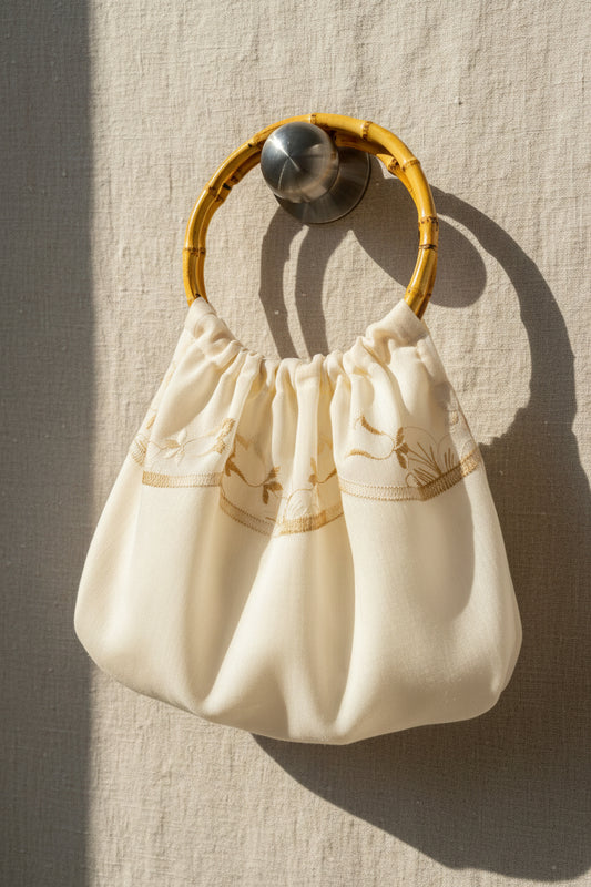 Small cream-colored handbag with a wooden handle on a textured beige background