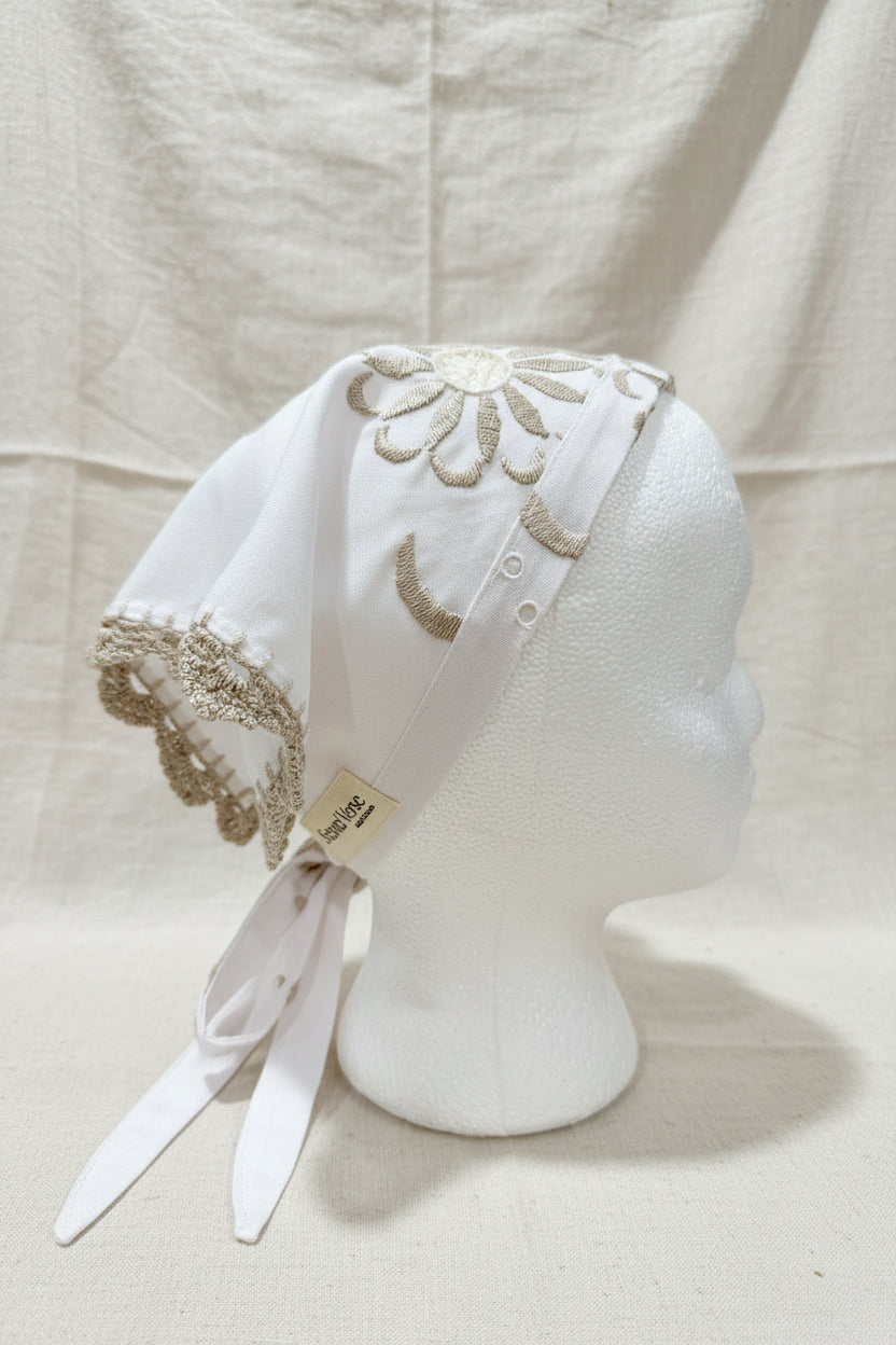 White hair scarf with embroidery on a mannequin head against a beige background